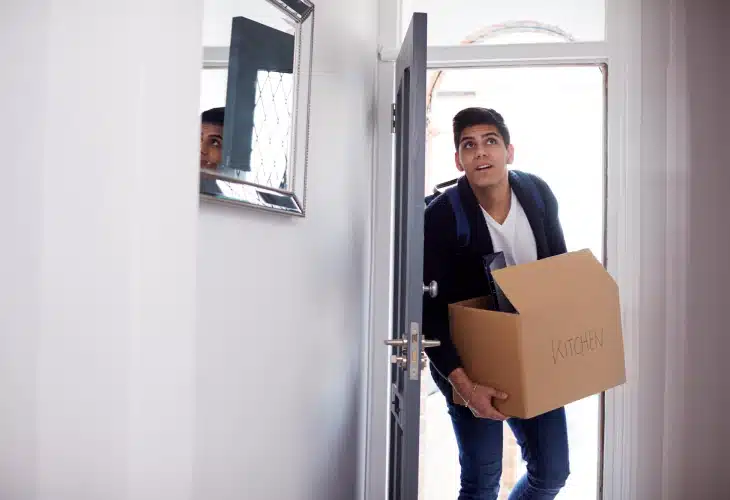 A guy entering house with a box